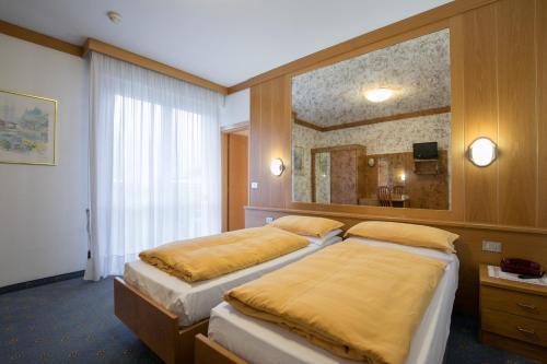 ein Hotelzimmer mit zwei Betten und einem Spiegel in der Unterkunft Vitalé Hotel Daniela in Levico Terme