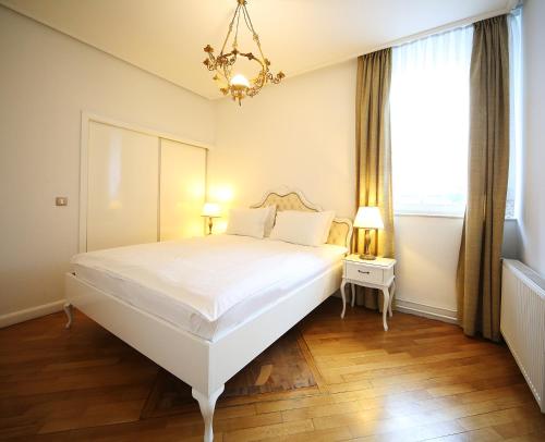 a bedroom with a large white bed and a chandelier at ApartHotel Vila Minka in Ljubljana