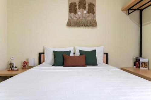 a white bed with green and white pillows on it at Rooms at Calma Villa Panorama, Batu Malang in Batu
