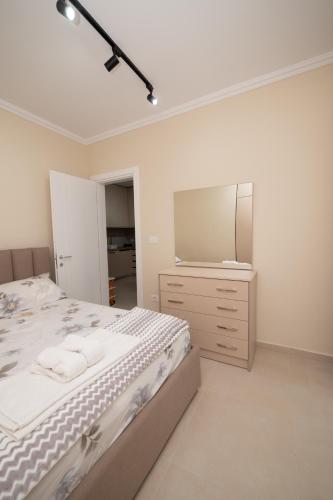 a white bedroom with a bed and a mirror at Golem Escape in Kavajë