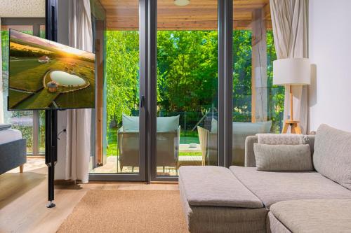 a living room with a couch and sliding glass doors at Chalets Franciska Major, Pro Village in Sopronkövesd