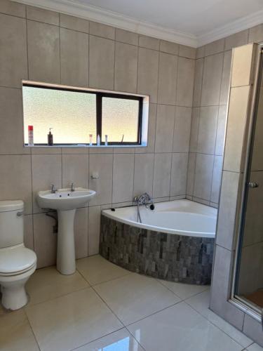 a bathroom with a tub and a toilet and a sink at Urban Rest Guesthouse in Mahikeng