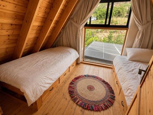 two beds in a room with a window at M Place in Shārūn