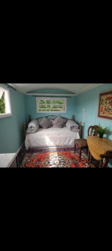 a bedroom with a bed and a table and two windows at Rowan retreat,Renwick, Penrith,CA10 1LA in Penrith