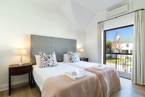 a bedroom with two beds and a large window at Winelands Golf Lodges 11 in Stellenbosch