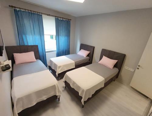 two beds in a room with blue curtains at Blacktree Edirne in Edirne