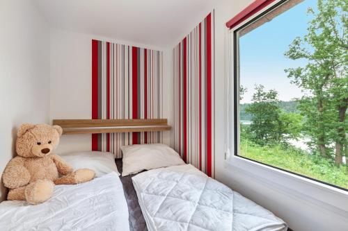 a teddy bear sitting on a bed next to a window at Ferienhaus 257 in Zadelsdorf
