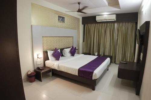 a bedroom with a large bed with purple pillows at Hotel highway inn in Gandhidham