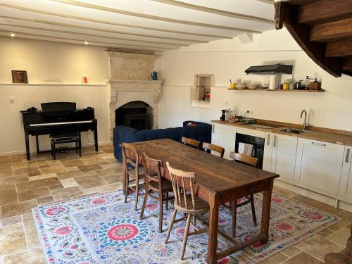 a kitchen and dining room with a table and a piano at La Maison des Sources in Édon