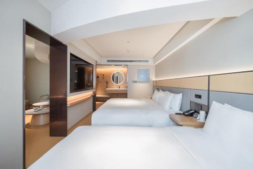 a hotel room with two beds and a television at JI Hotel Beijing Panjiayuan in Beijing