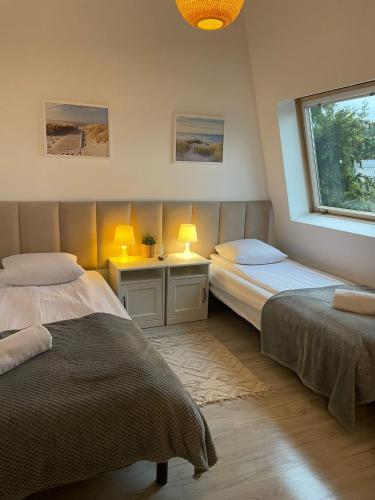 a bedroom with two beds and a window and two lamps at Ośrodek Delfin in Dąbki