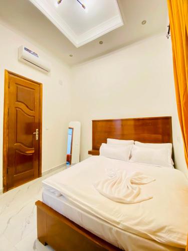 a bedroom with a large white bed with a wooden headboard at Résidence moncloa in Brazzaville