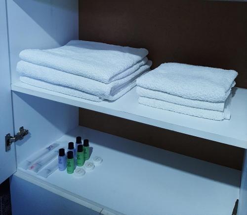 ein Badezimmer mit Handtüchern und Flaschen auf einem Regal in der Unterkunft Lellia in Martvili