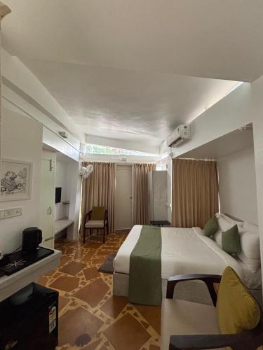 a hotel room with a large bed and a chair at Trisara Boutique Stay in Mysore