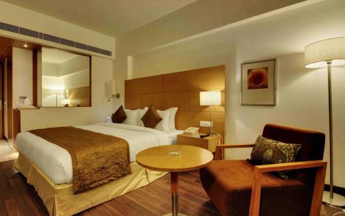 ein Hotelzimmer mit einem Bett, einem Tisch und einem Stuhl in der Unterkunft Hotel Platinum in Rajkot