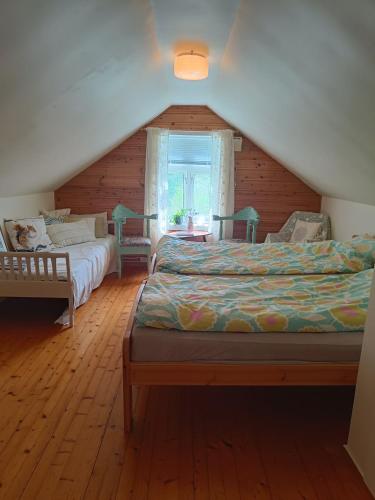 a attic bedroom with two beds and a window at Vakker perle nær sjøen in Villanger