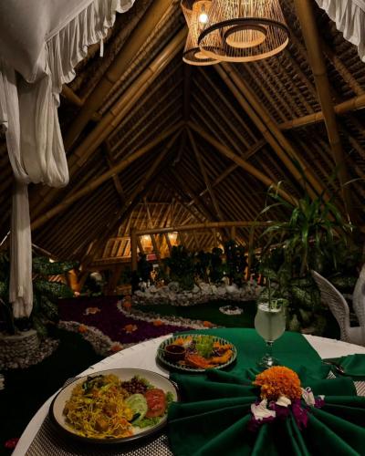 a table with plates of food on a green table cloth at Penida Bambu Green Suites in Nusa Penida