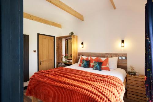 a bedroom with a large bed with an orange blanket at The Pig Arc in Bude