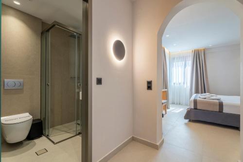 a bathroom with a shower and a toilet and a bed at Hotel Areti in Neos Marmaras