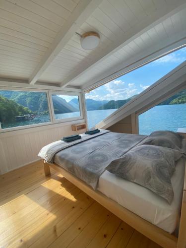 a bed on a boat with a large window at Viridian Three Boathouse Unique, PERUCAC in Perućac