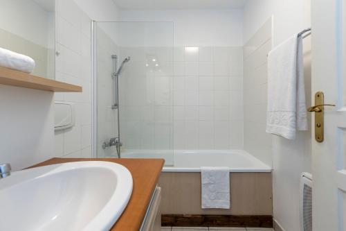 a white bathroom with a tub and a shower at Résidence Odalys Les Chalets d'Evian in Évian-les-Bains