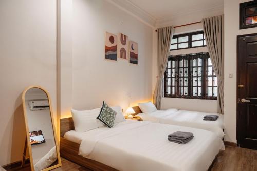 a bedroom with two beds and a mirror in it at Exia House in Ho Chi Minh City