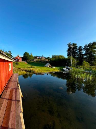 a pond with a red building and a red house at Jennys tent in Saltvik