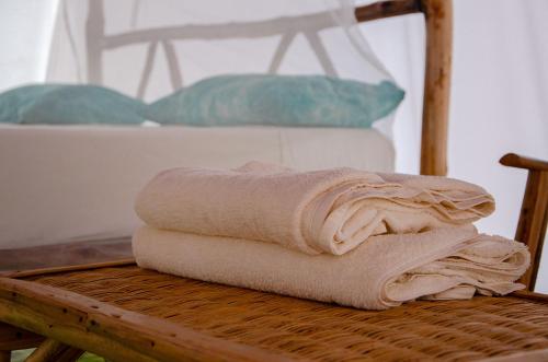 a stack of towels sitting on a wooden table at Eden Lodge - Desert Camp in Kébémèr