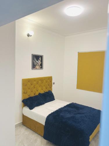 a bedroom with a bed with a blue blanket at His Goodness - Apt Two! in Kampala