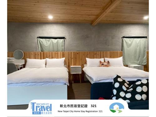 a bedroom with two beds with a dog laying on the pillows at Lucky House B&B in Jiufen