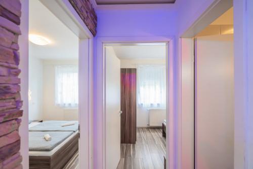 a room with purple walls and a bedroom with a bed at AH-Corso Wellness Apartment in Siófok