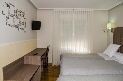 a room with two beds and a desk and a television at Hotel Presa in Riaño