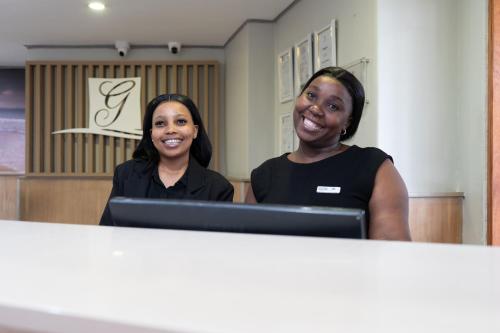 two women are smiling in front of a computer at Gooderson Tropicana Hotel in Durban