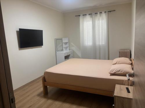 a bedroom with a bed and a flat screen tv at SARA in Ðuranovići