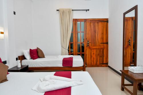 a bedroom with two beds and a wooden door at Bay Marina in Arugam Bay
