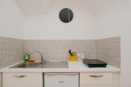 a kitchen counter with a sink and a clock on the wall at Casetta Puntino in Atrani
