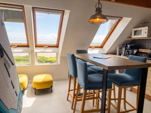 a kitchen with a table and chairs and windows at Appartement charmant à Sarzeau avec vue sur la mer, 55 m² in Sarzeau