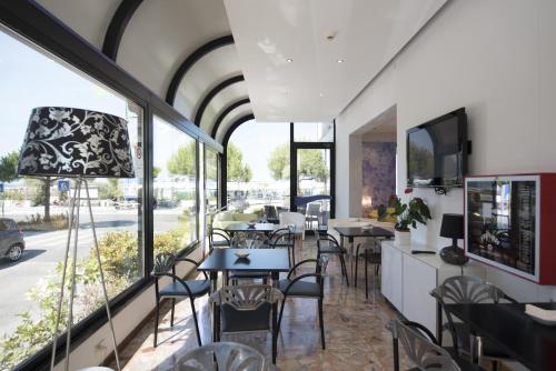 een restaurant met tafels, stoelen en ramen bij Hotel Iride & Spa in Cesenatico