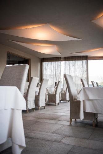 a room with white chairs and tables and windows at Das Panorama Dependance in Caldaro