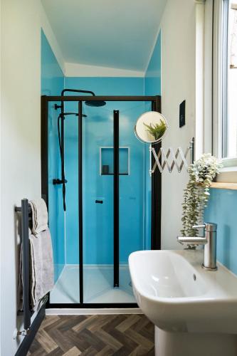 a bathroom with a glass shower and a sink at The Piggery at Little Pig in Bude