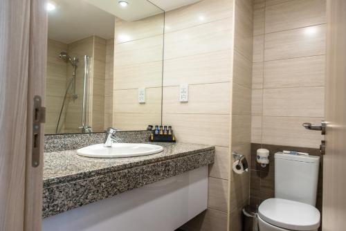 a bathroom with a sink and a toilet at Cynthiana Beach Hotel in Paphos City