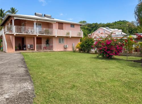a pink house with a large yard with flowers at Appartement 3 chambres à Ducos in Ducos