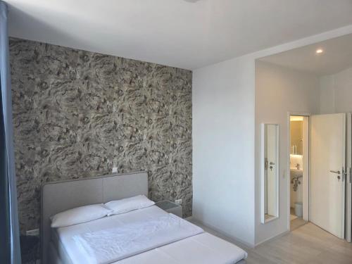 a bedroom with a white bed and a wall at City Hotel in Rheinfelden