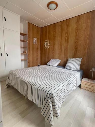 a bedroom with a large bed with a wooden wall at Maison La Petite Pause in Bray-Dunes