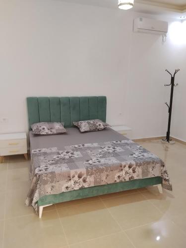 a bed with a green headboard in a room at villa mimosa free parking inside in Tataouine