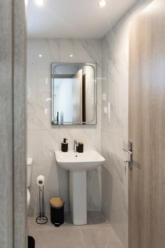 a white bathroom with a sink and a mirror at Beautiful Apartment in Larisa