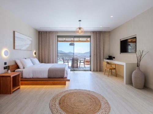 a bedroom with a bed and a desk with a view at Vinara Luxury Suites Mykonos in Mykonos