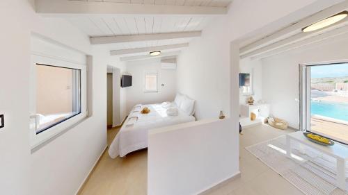 a white bedroom with a bed and a large window at Okto in Archangelos