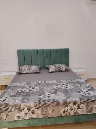a bed with a green headboard and two pillows at villa mimosa free parking inside in Tataouine