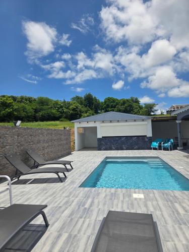 a patio with a swimming pool and chairs and a building at VILLA Orchidée in Le Moule